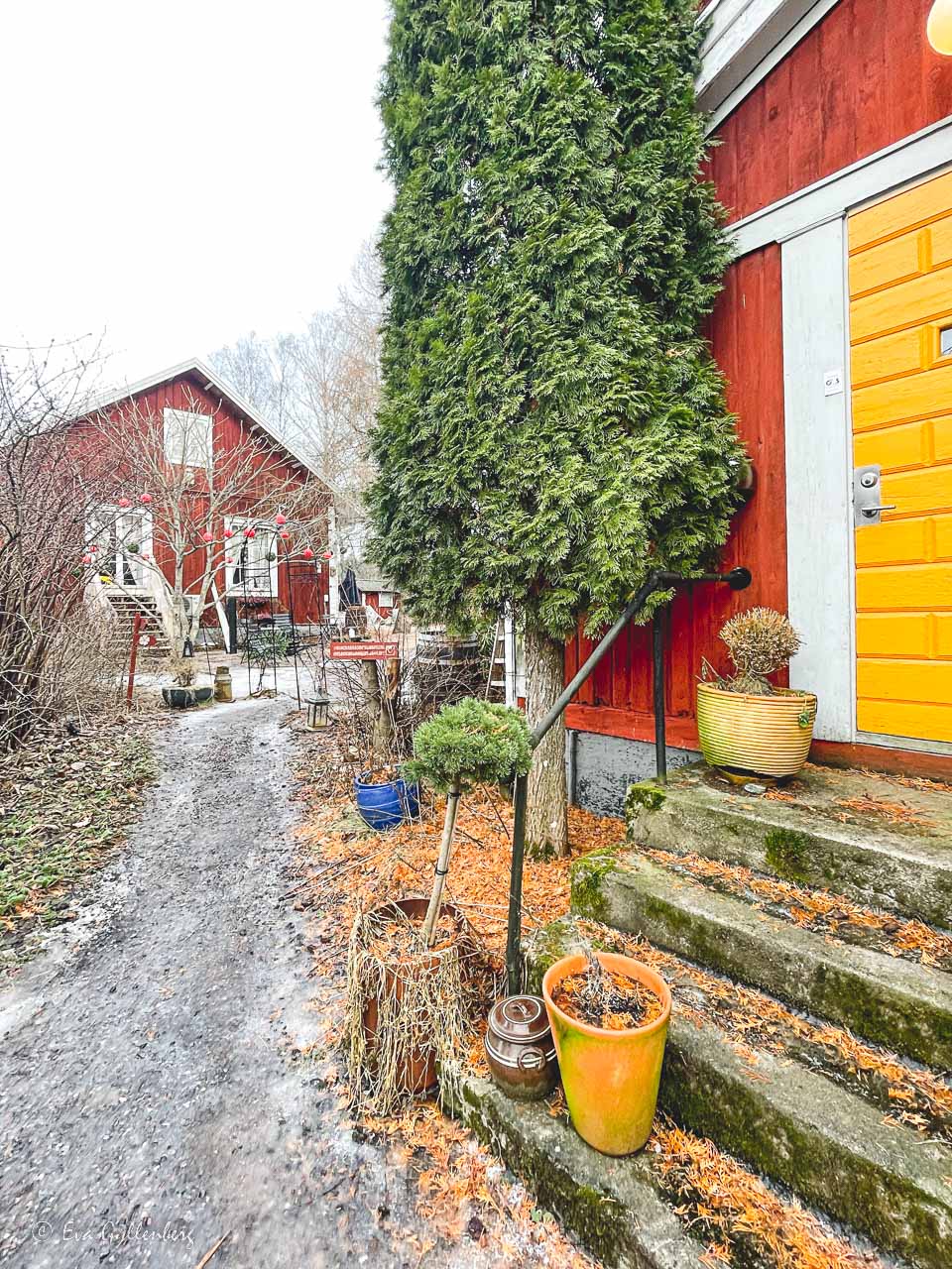 Två röda trähus med en gul dörr och en trappa