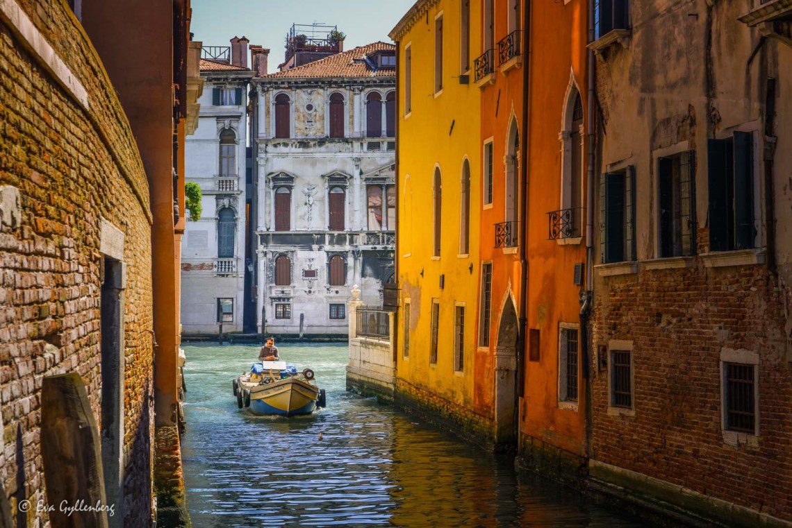 Båt i liten kanal i Venedig