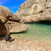 Tjej på stranden vid det turkosa vattnet i viken Wied il-Ghasri - Gozo
