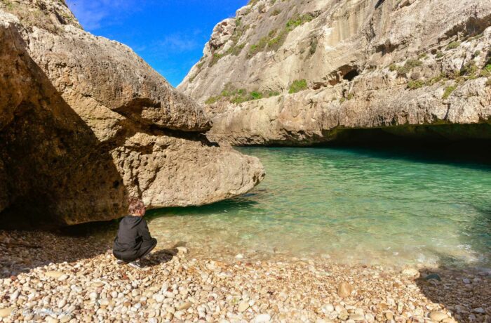 Girl on the beach by the turquoise water in viken Wied il-Ghasri - Gozo
