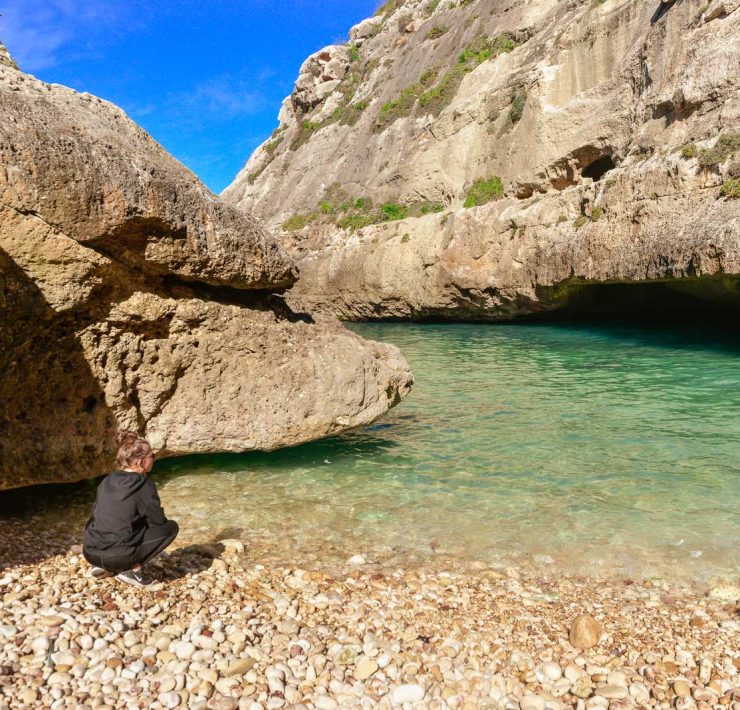 Tjej på stranden vid det turkosa vattnet i viken Wied il-Ghasri - Gozo