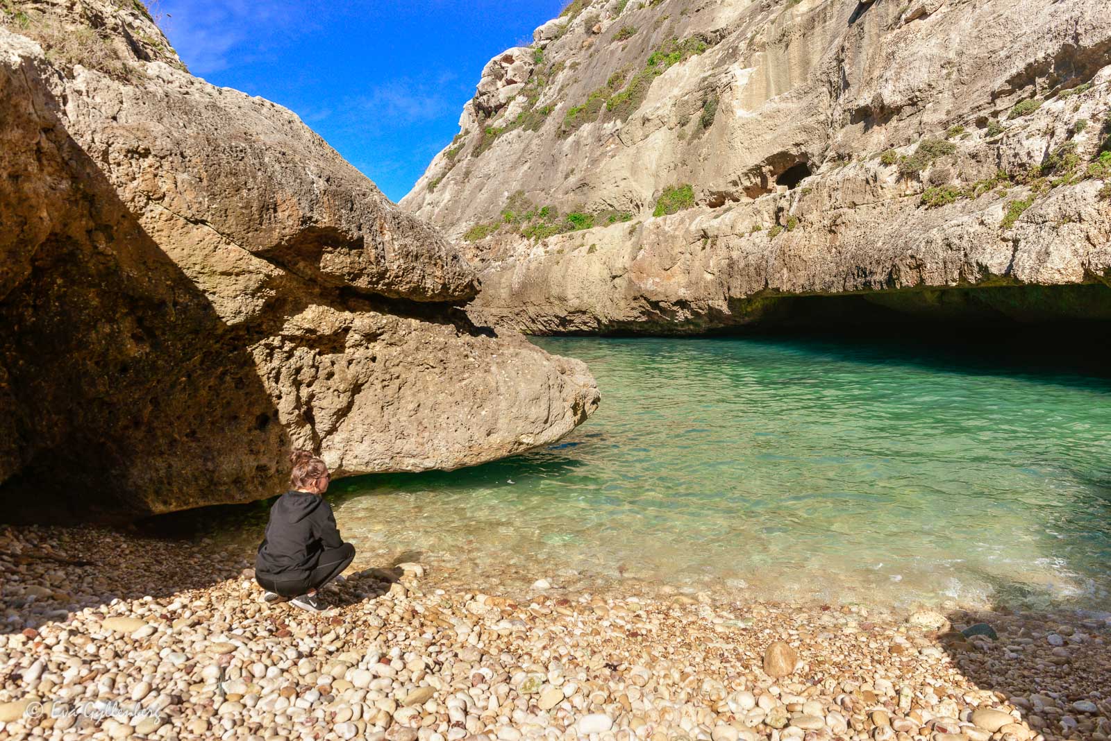 Tjej på stranden vid det turkosa vattnet i viken Wied il-Ghasri - Gozo