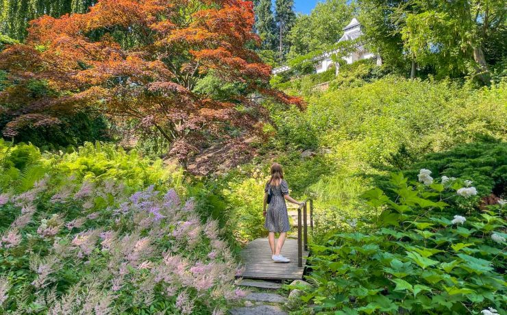 Kvinna i klänning på en bro i den japanska trädgården