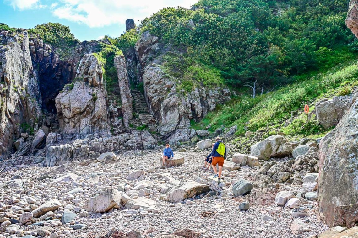 Människor sitter på en klippstrand vid Kullaberg