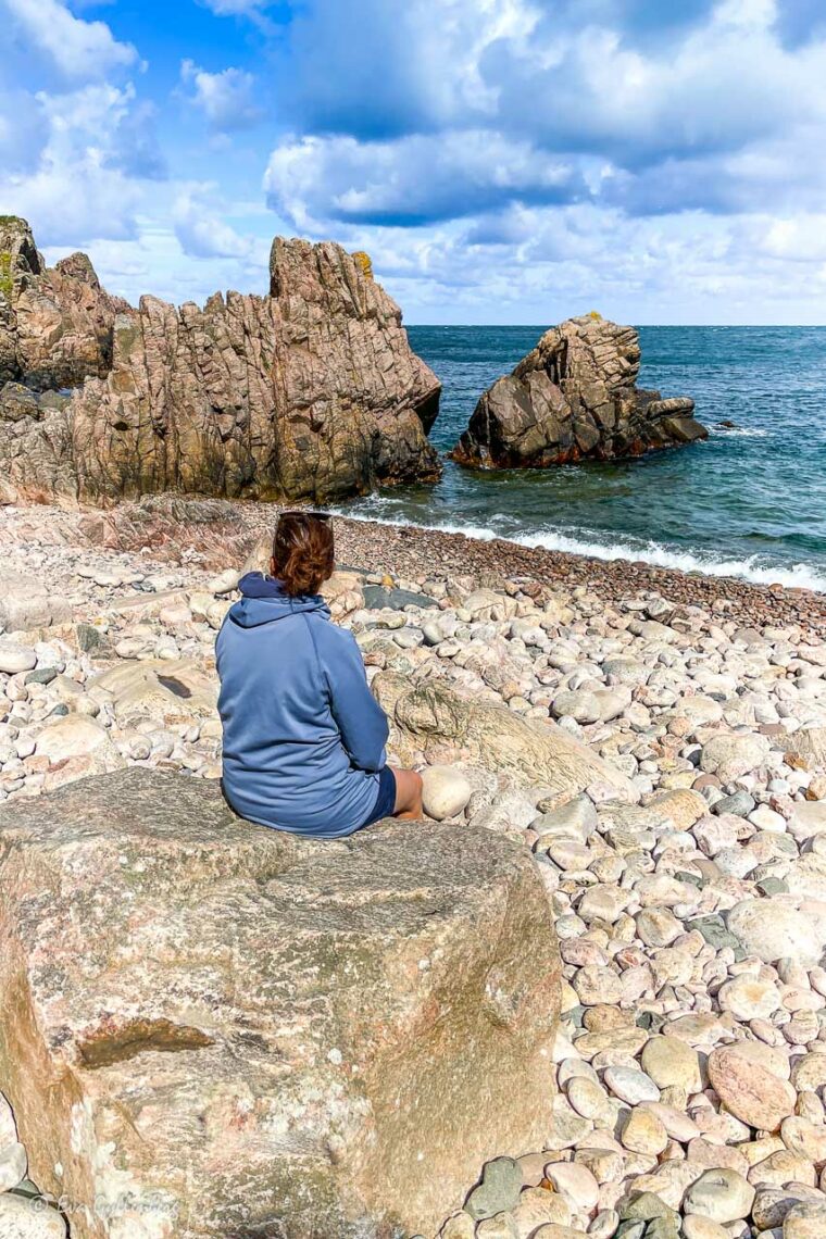 Kvinna sitter på stranden i solskenet