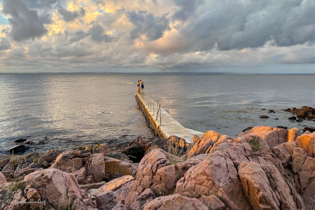 Badbryggan med badare med dramatisk himmel i Skäret