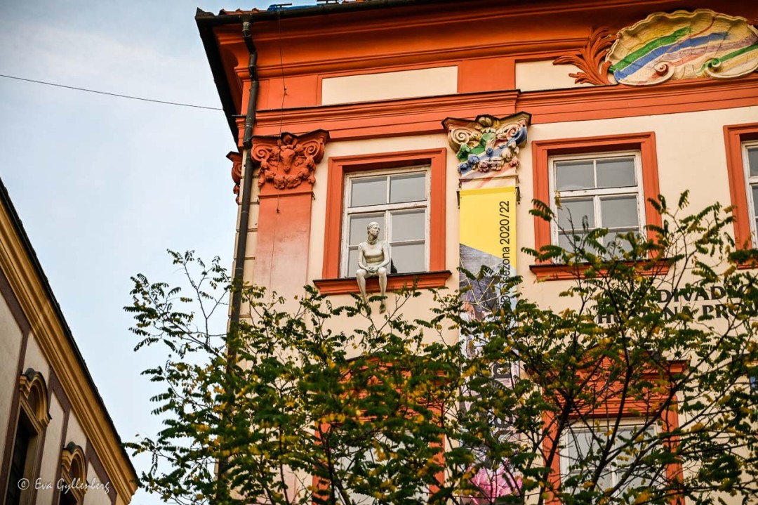 en staty av en människa som sitter i ett fönster