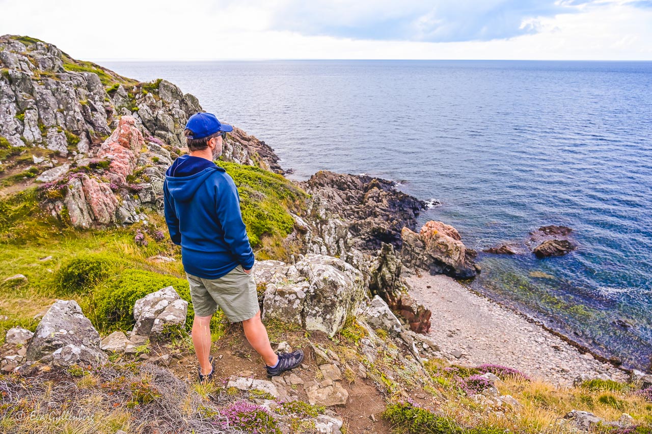 Man stående och ser ut över havet från en klippa