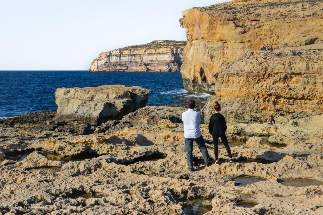 Två personer står vid platsen där Azurfönstret tidigare låg - en av alla sevärdheter på Gozo