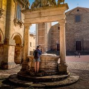 Flicka tittar ner i brunn på torget i Montepulciano