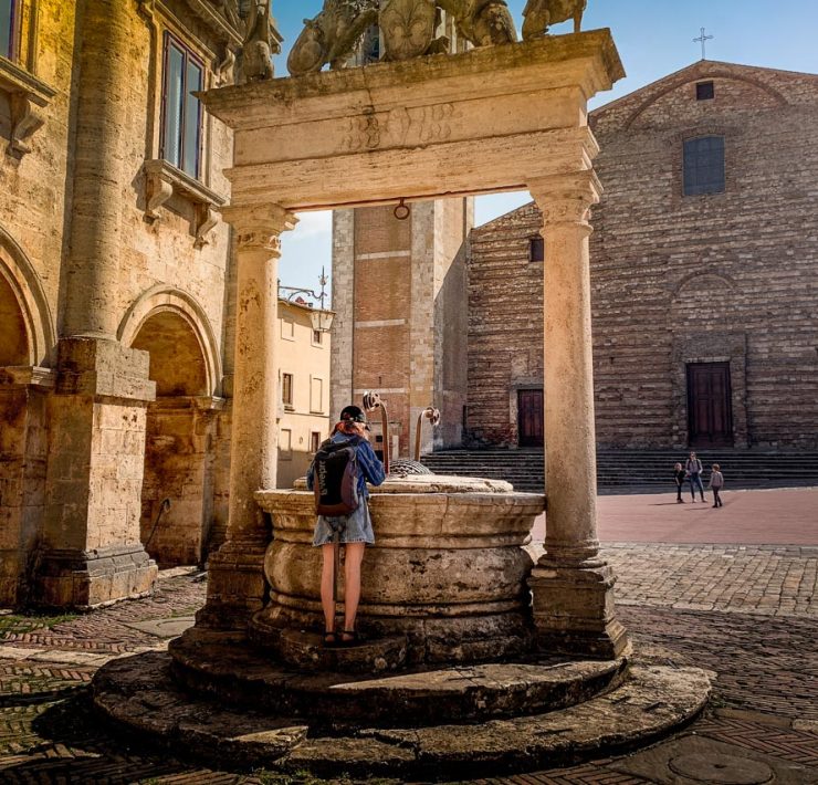 Flicka tittar ner i brunn på torget i Montepulciano