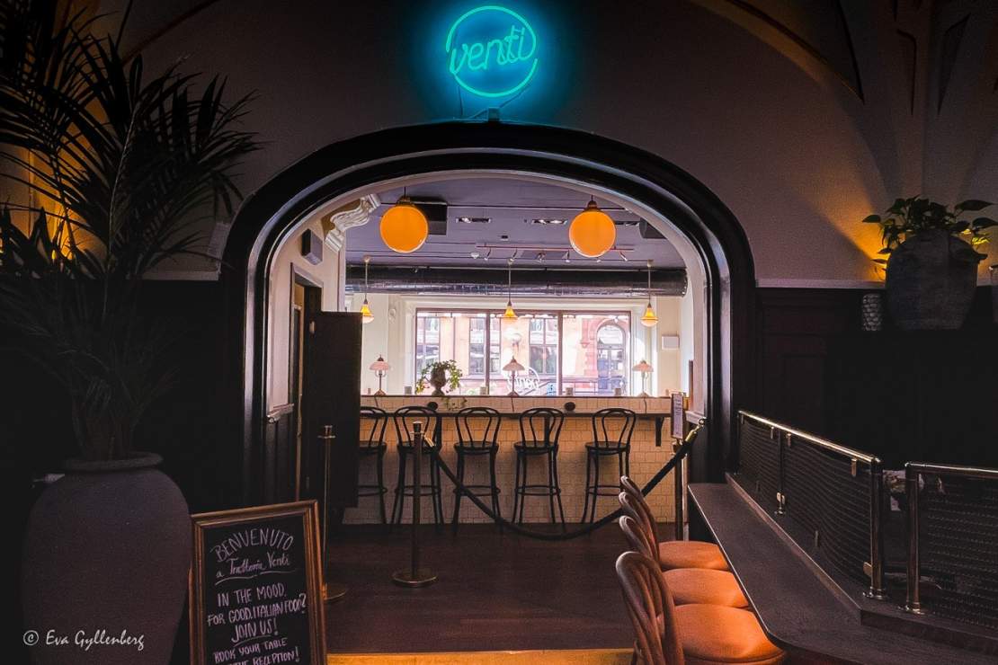Restaurang med blå neonskylt och svarta höga barstolar