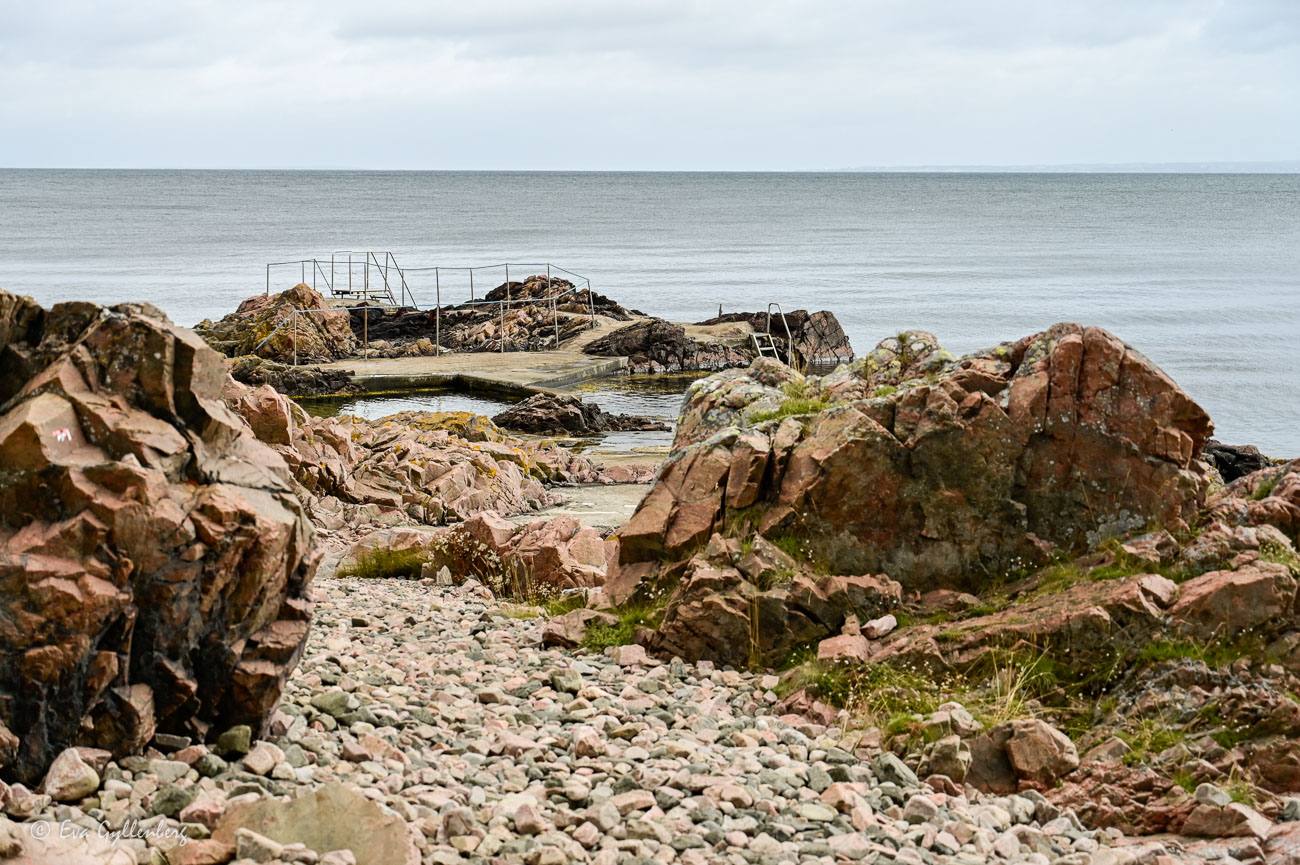 Badplats vid röda klippor och lugnt hav