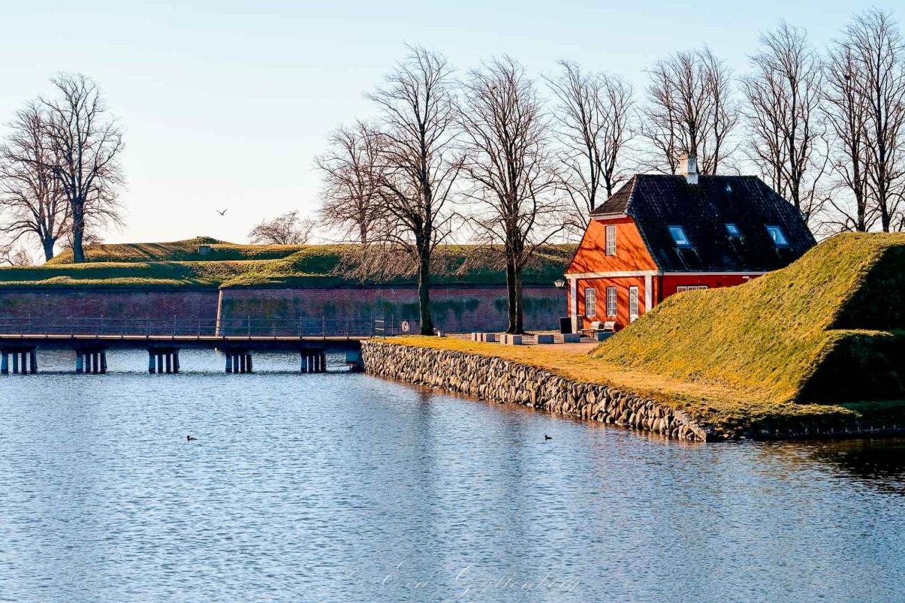Rött litet hus vid vatten och bro