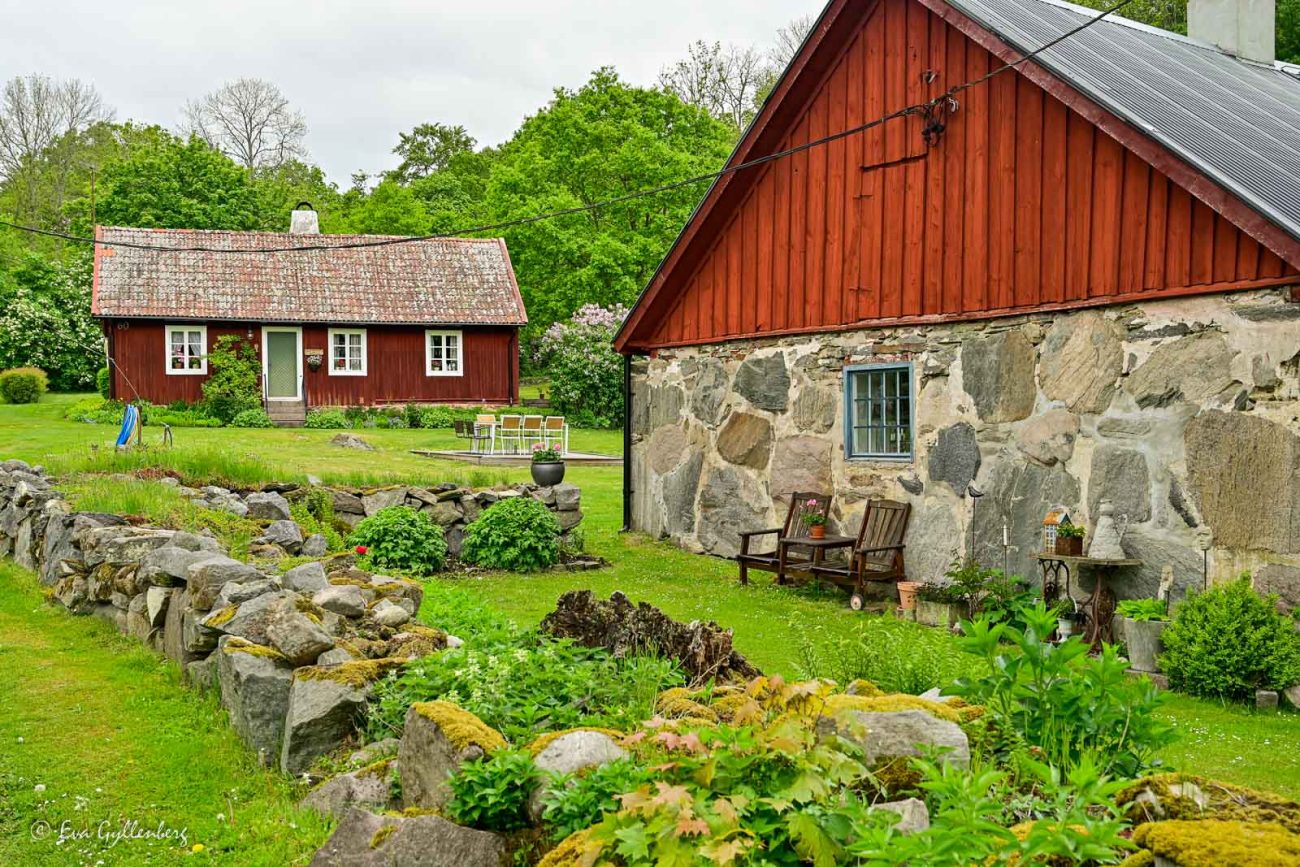 Röd stuga med en bondgård med två loungestolar