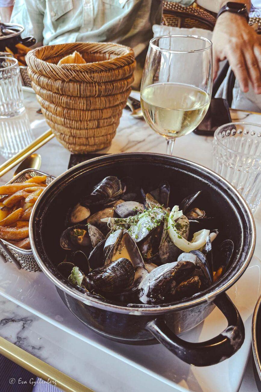 Blåmusslor i en Moules à la normande på ett bord med ett glas vin