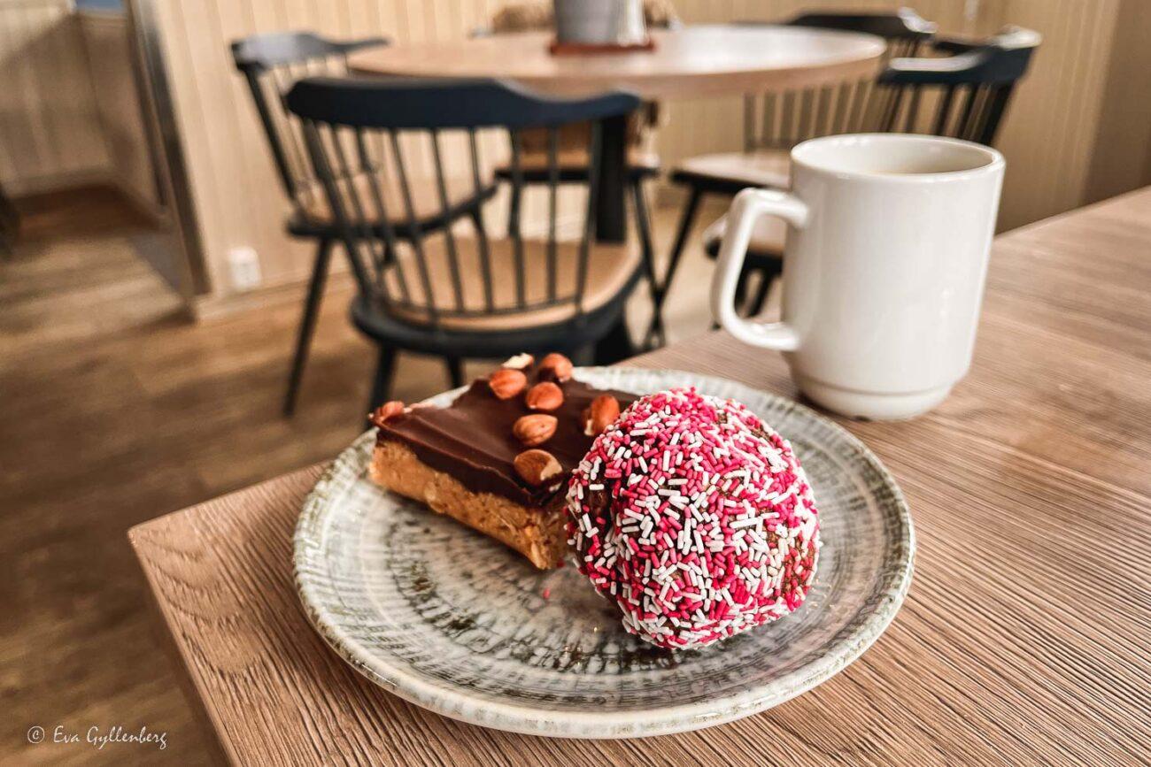 Chokladboll med polkaströssel och en snickersbakelse på ett bord med en kaffekopp
