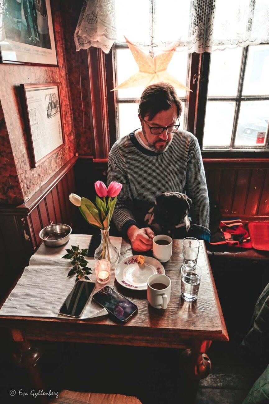 Hund och man fikar inuti Hamncaféet