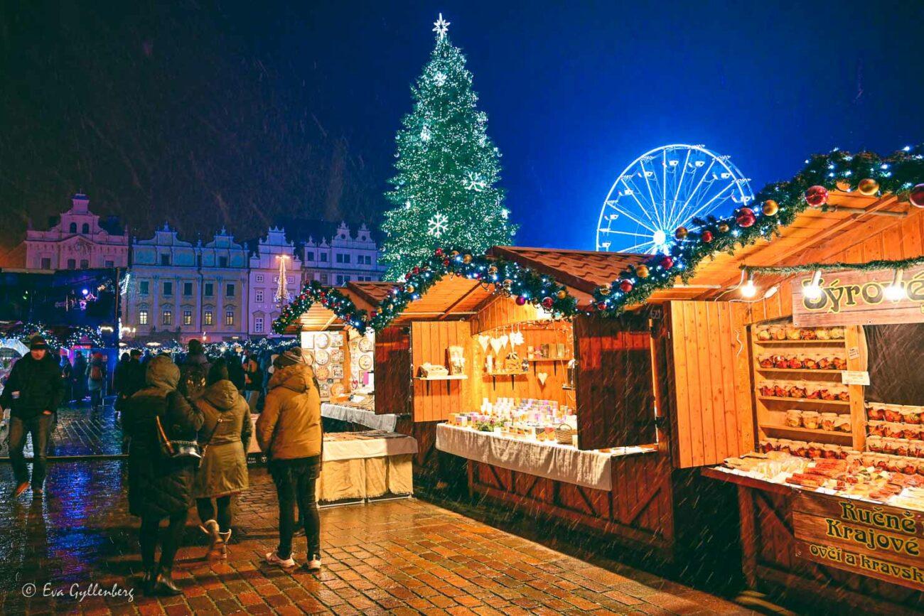 snöig julmarknad i mörker med upplyst gran och massor av lampor
