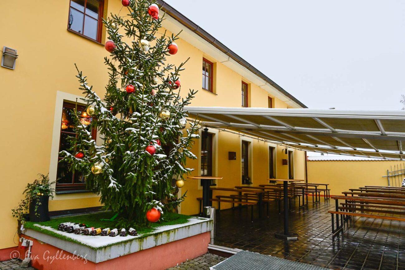 Julgran täckt med snö utanför ett bryggeri med uteservering