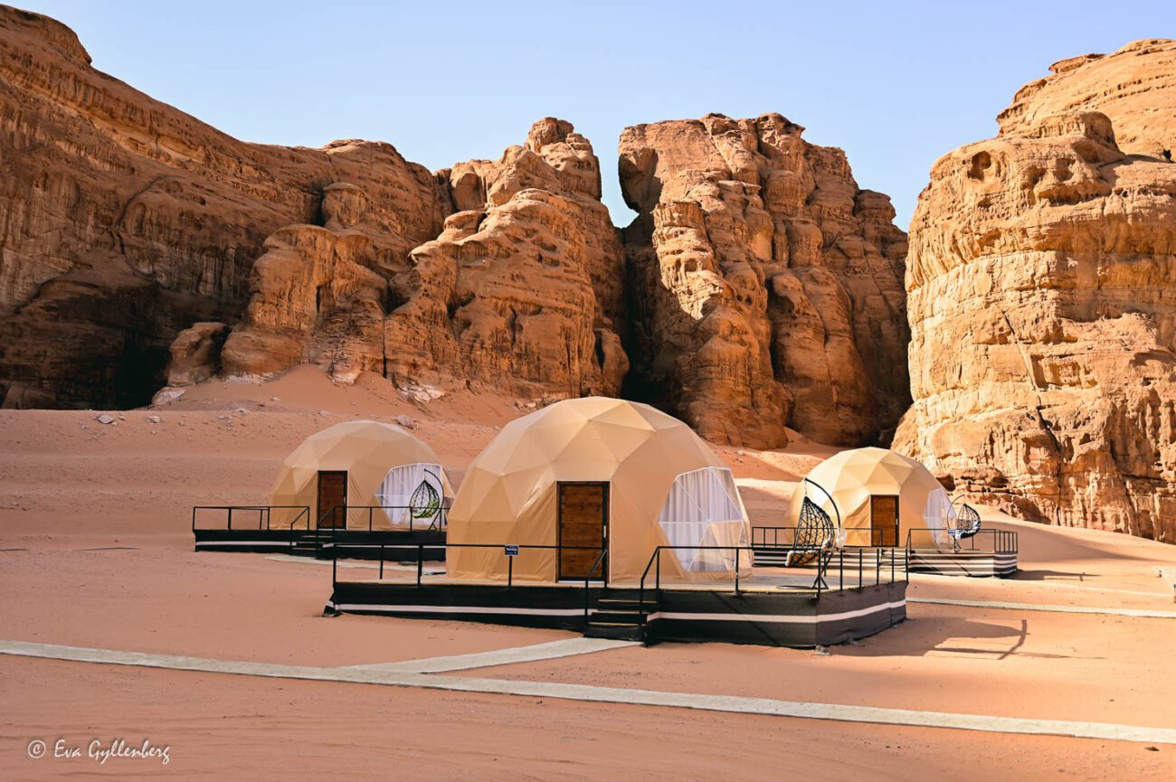 Three capsule hotels in the form of igloos in the desert under steep cliffs