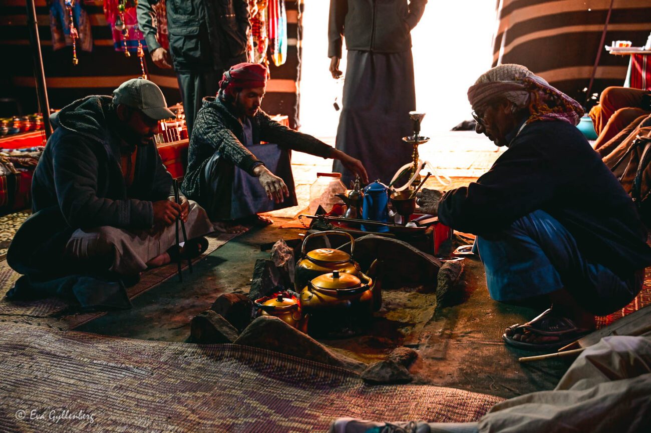 Tre beduiner i ett tält kokar kaffe i kopparkittlar