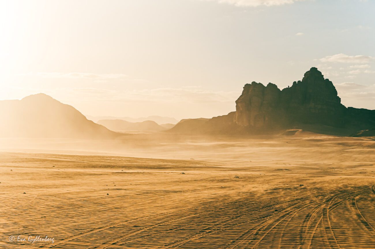The sand swirls in the desert among dark rocks