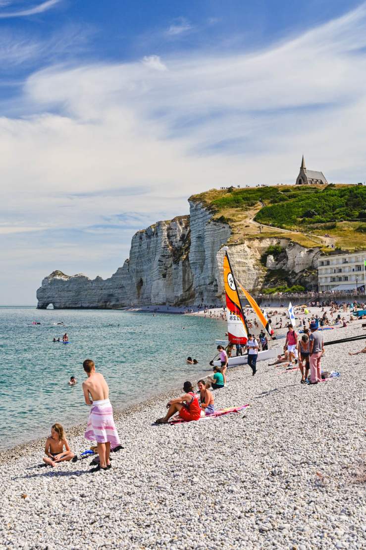 Stranden, havet och klippan i Étretat med en massa badande besökare
