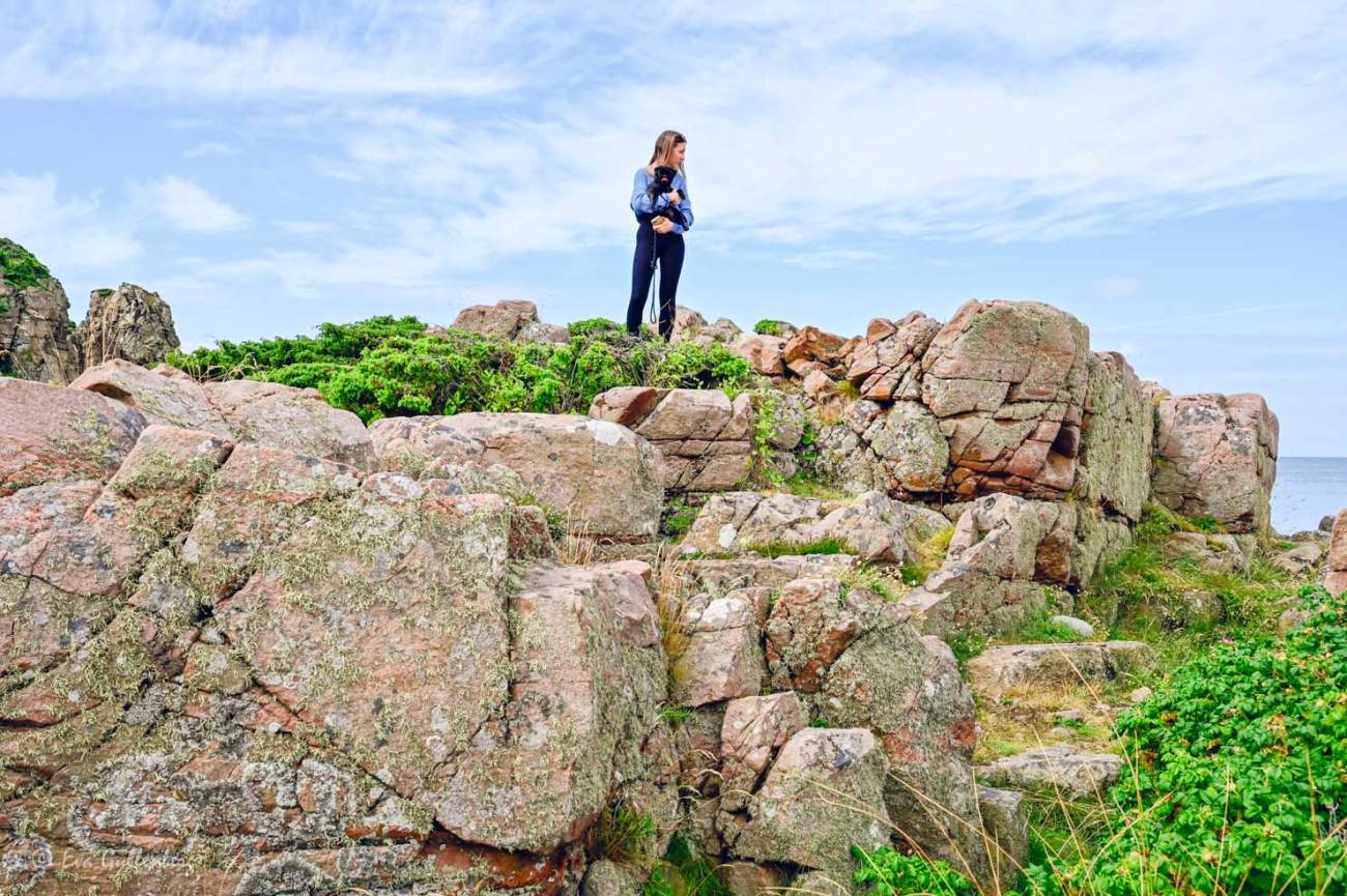 Tjej med hund står på toppen av en rosa klippa vid Bjärekustens naturreservat