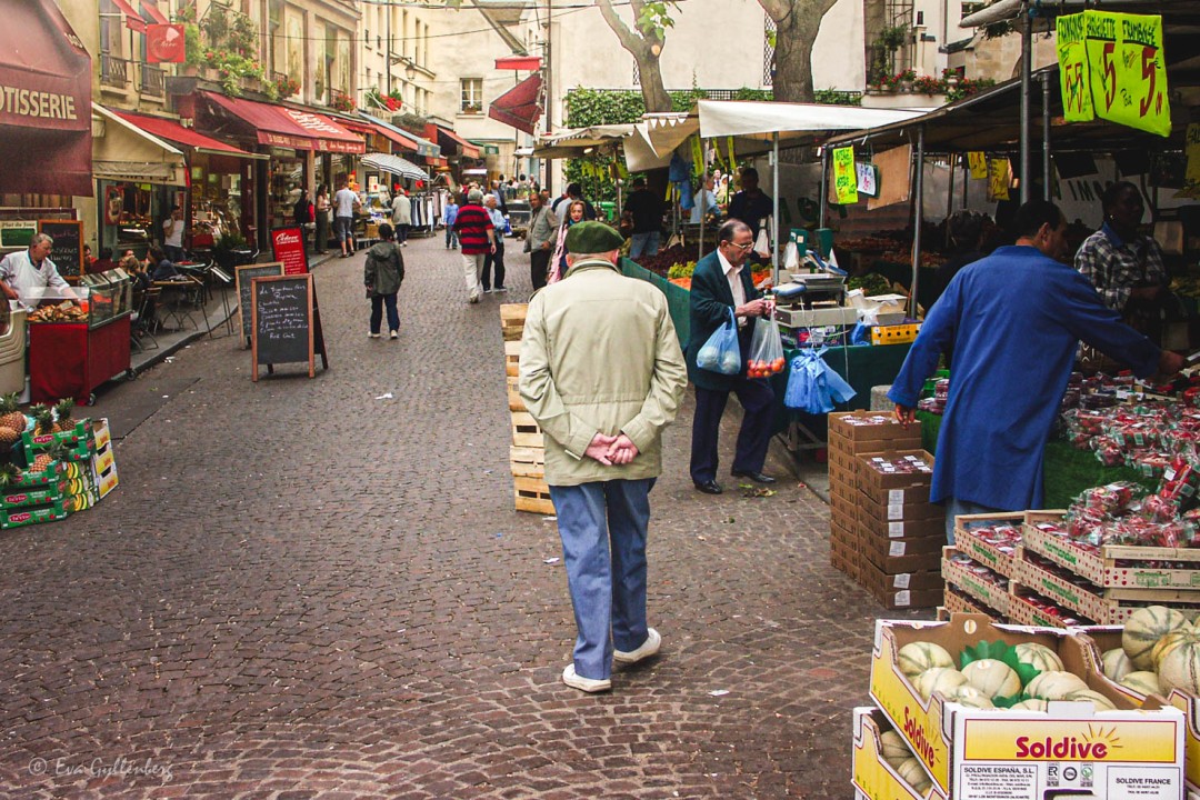 Man med basker strosar längs marknaden på Rue Mouffetard