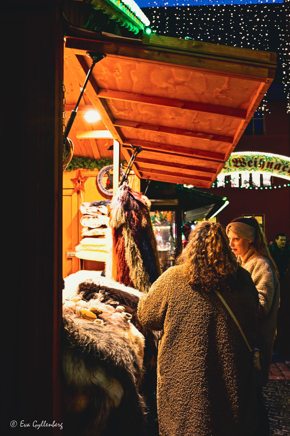 Två kvinnor tittar på lammfällar på en julmarknad