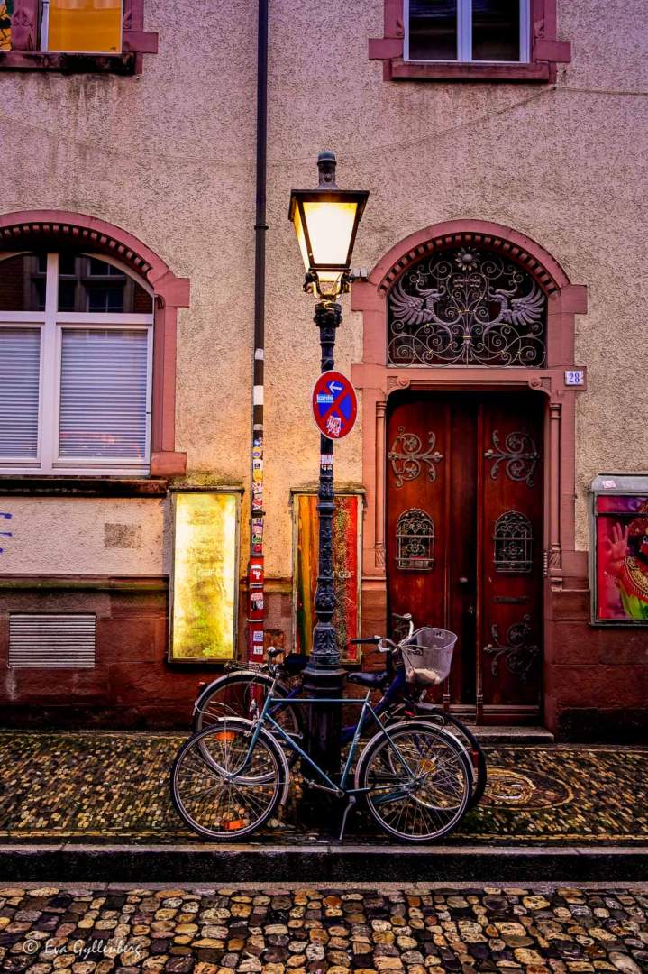 Cyklar parkerade vid en lyktstolpe vid ett rosa hus