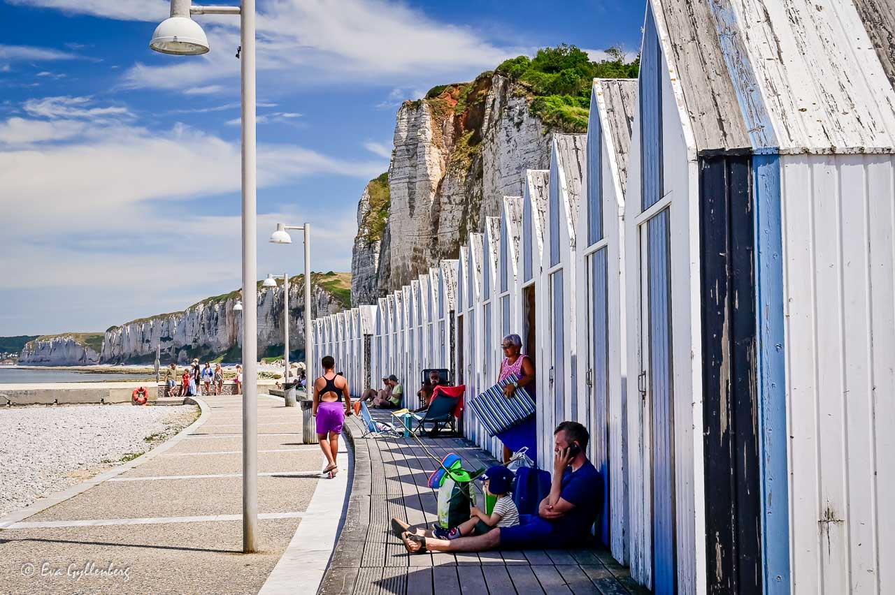 Den vita stenstranden i Yport med de blåvita badhytterna och de vita kalkstensklipporna bakom.