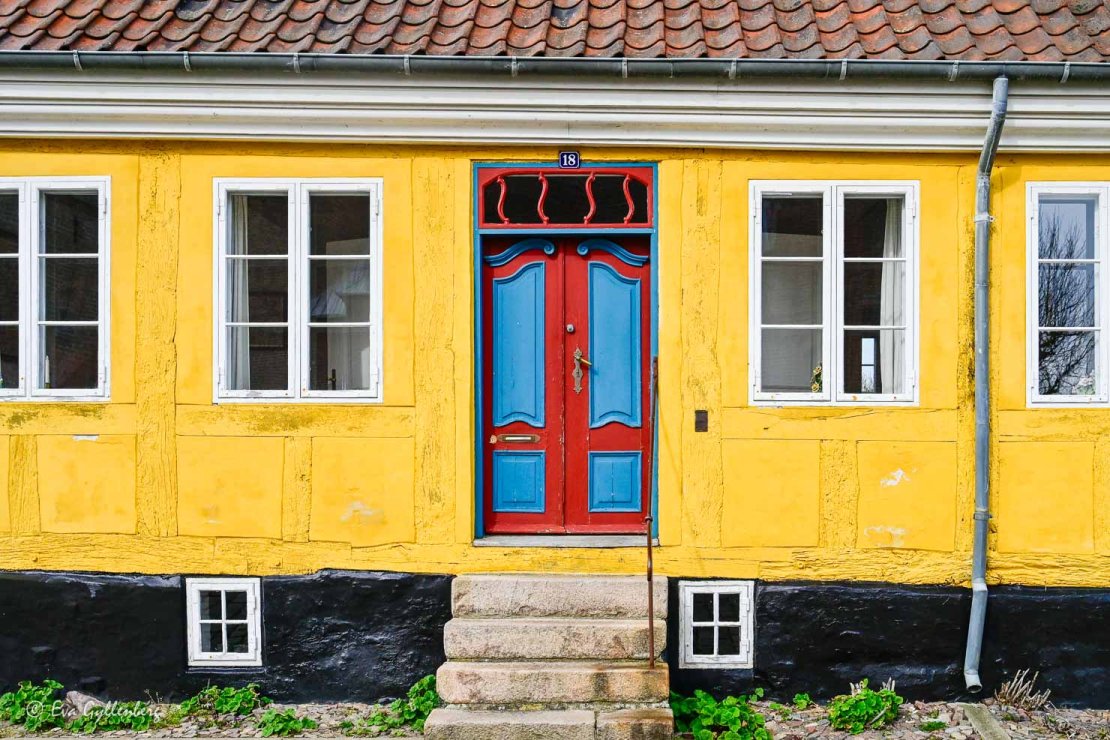 gult hus med röd/blå dörr